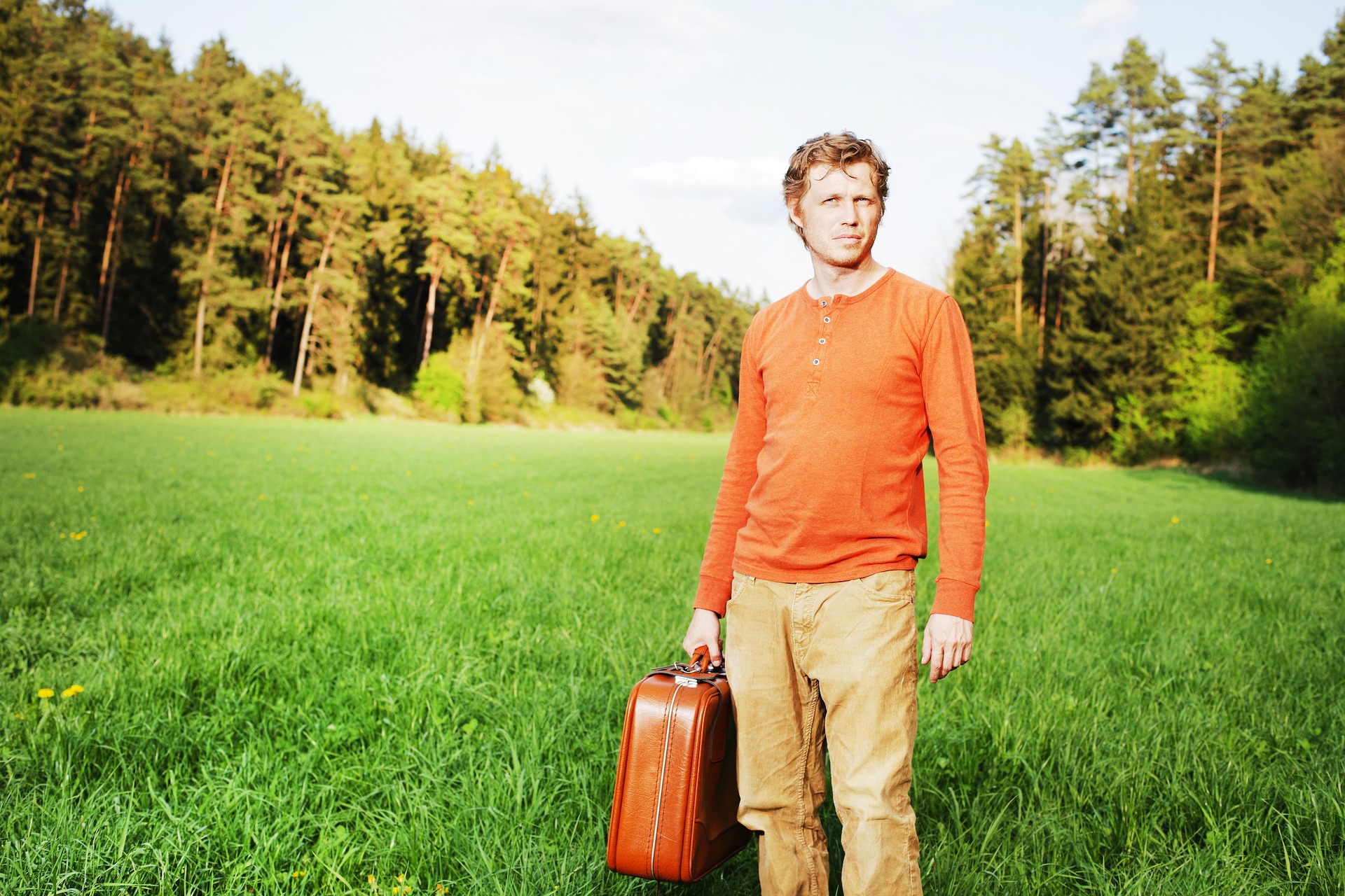 Mężczyzna z walizką stojący na polanie